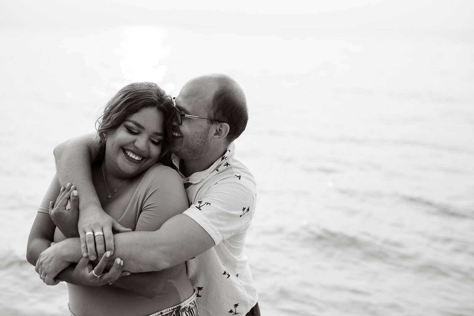 A couple warmly embraces in the ocean at west bay beach in roatan honduras in black and white