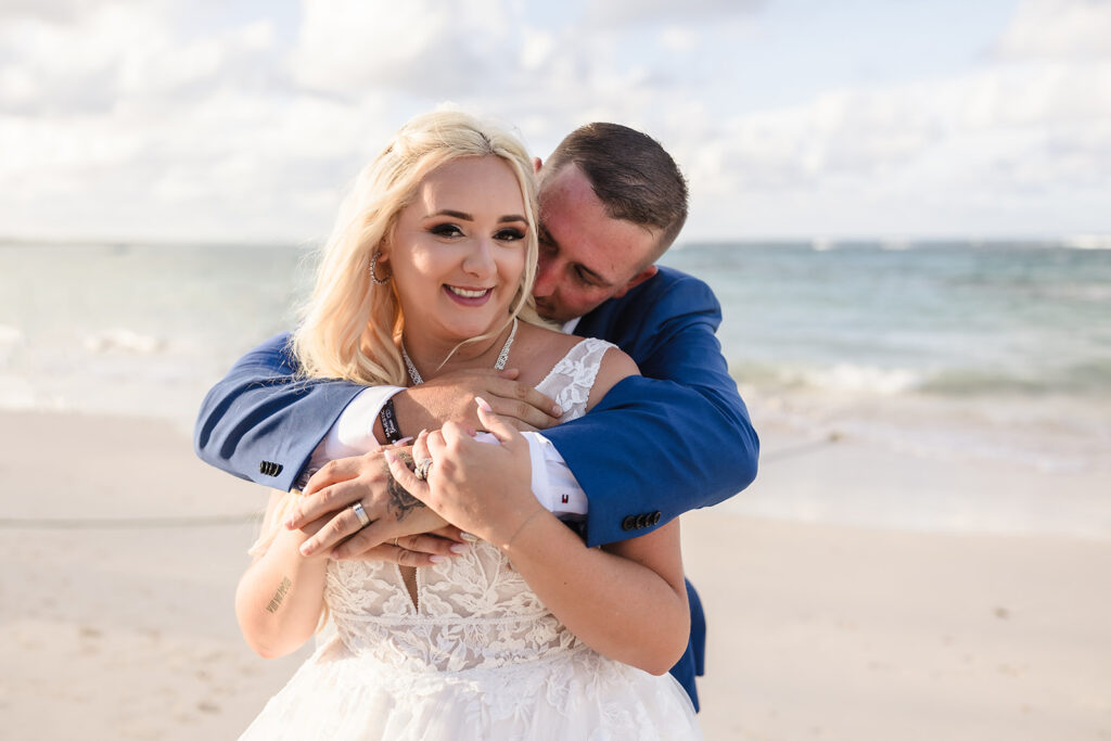 A bride and groom hug on a beach at their Roatan wedding.