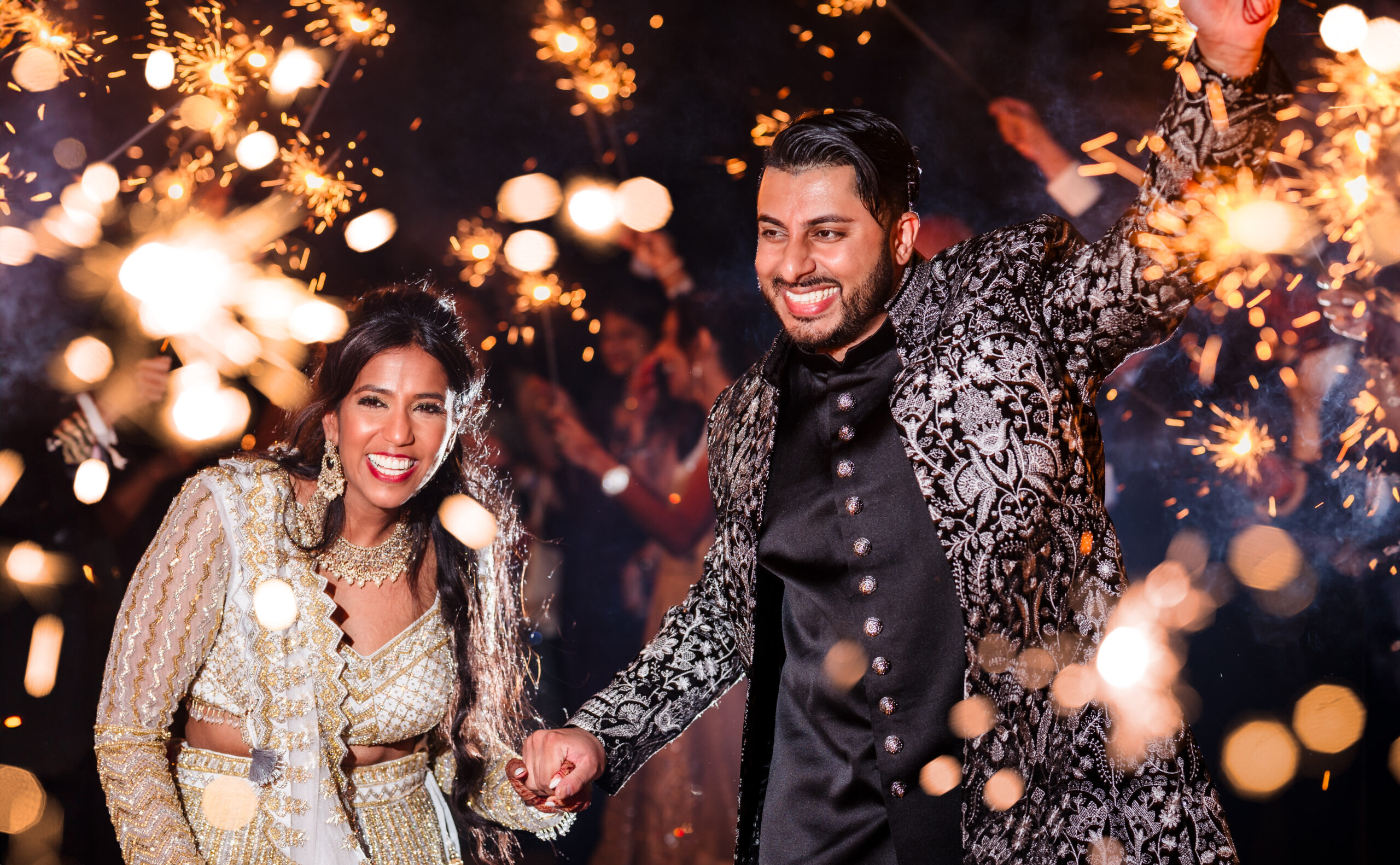 A bride and groom exit through a sparkler tunnel.
