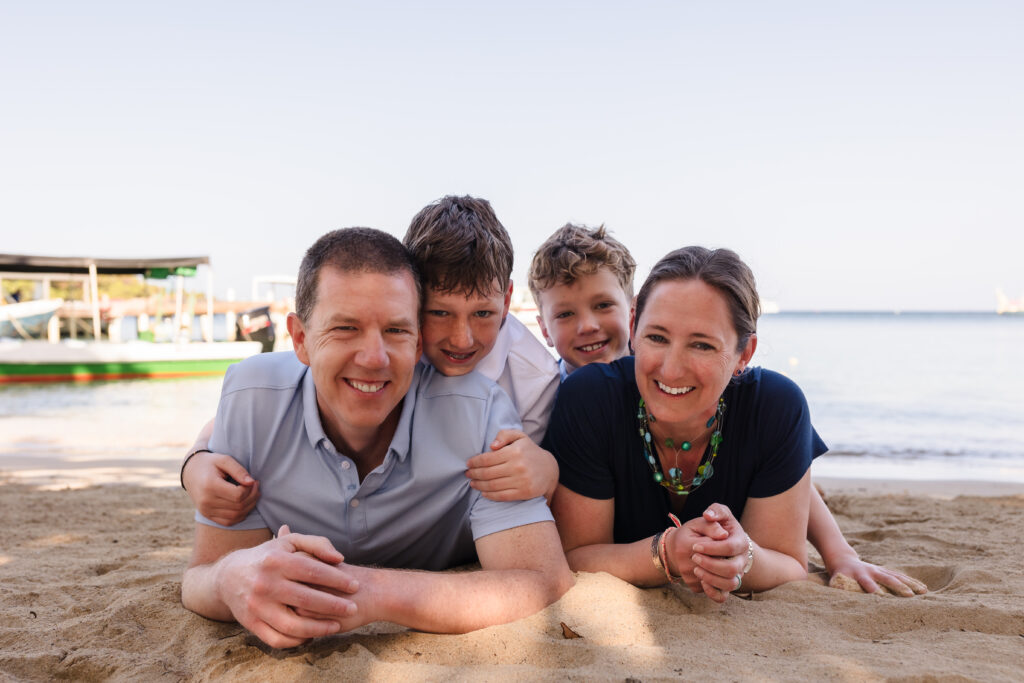 A couple and their sons laying on the beach.