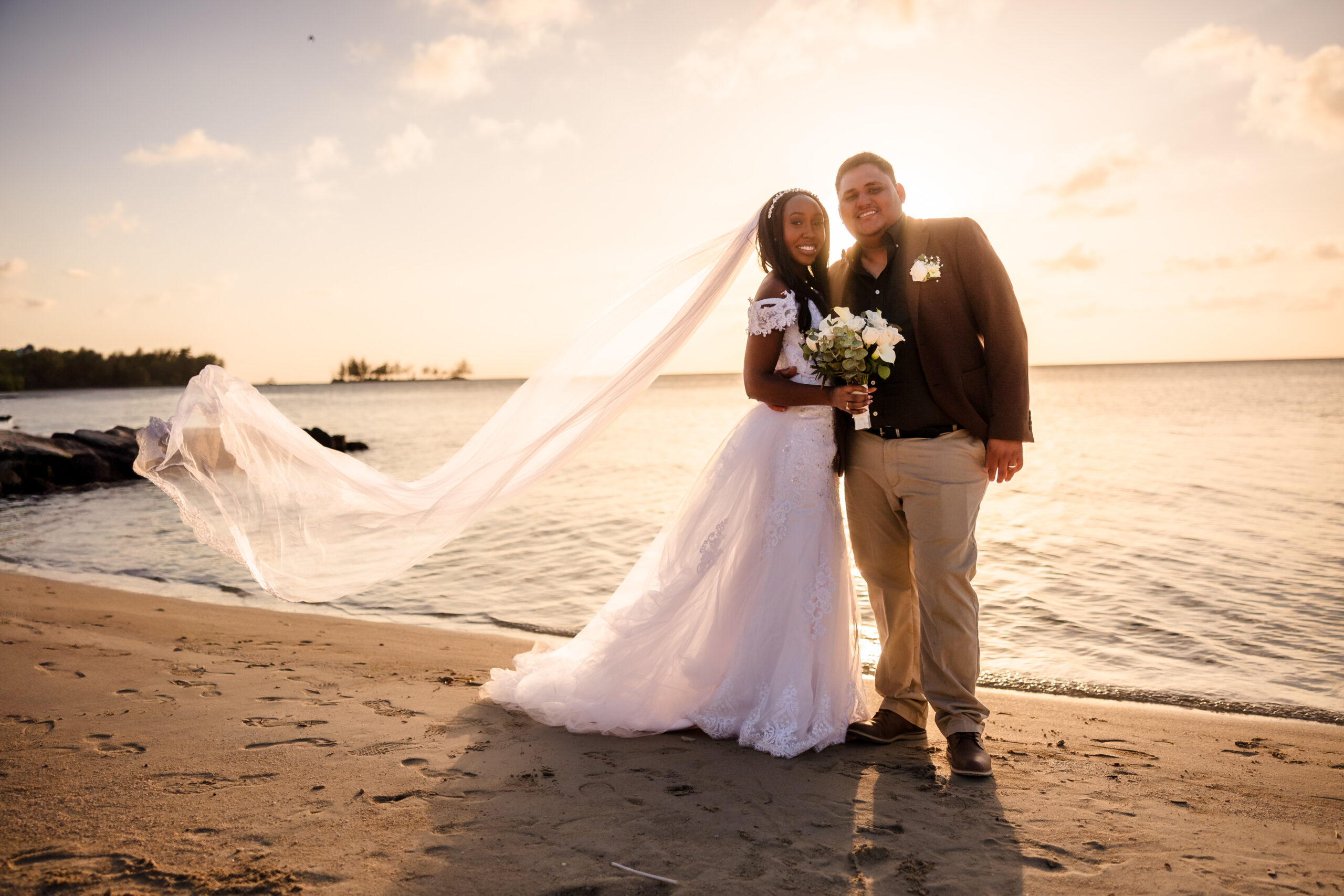 A portrait of the bride and groom on the beach at sunset.