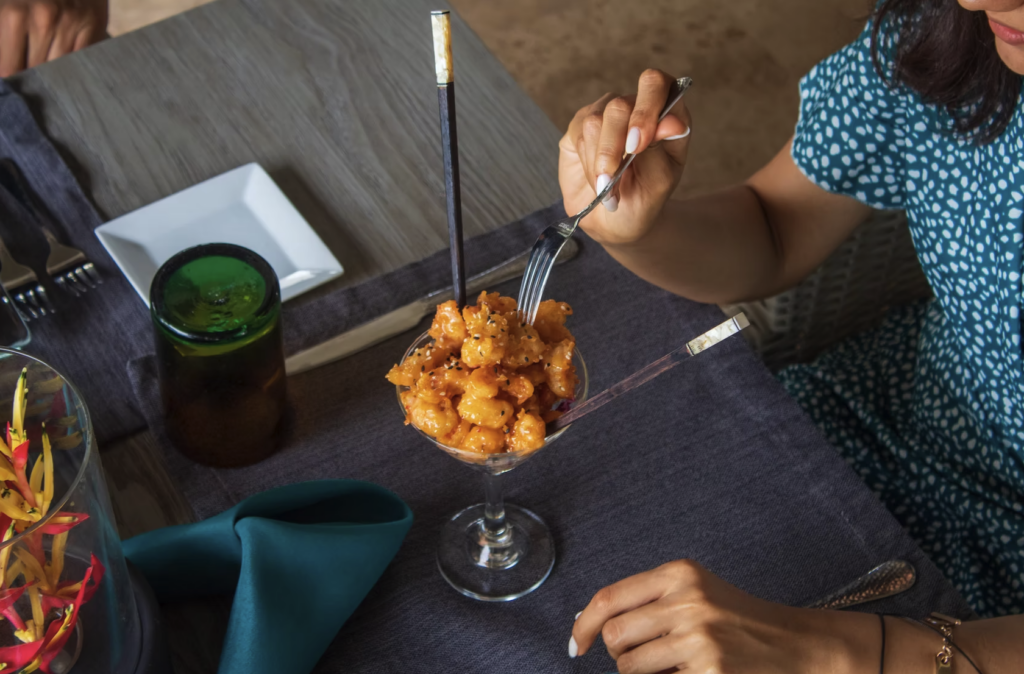 A woman eating seafood at Lotus by Xbalanque
