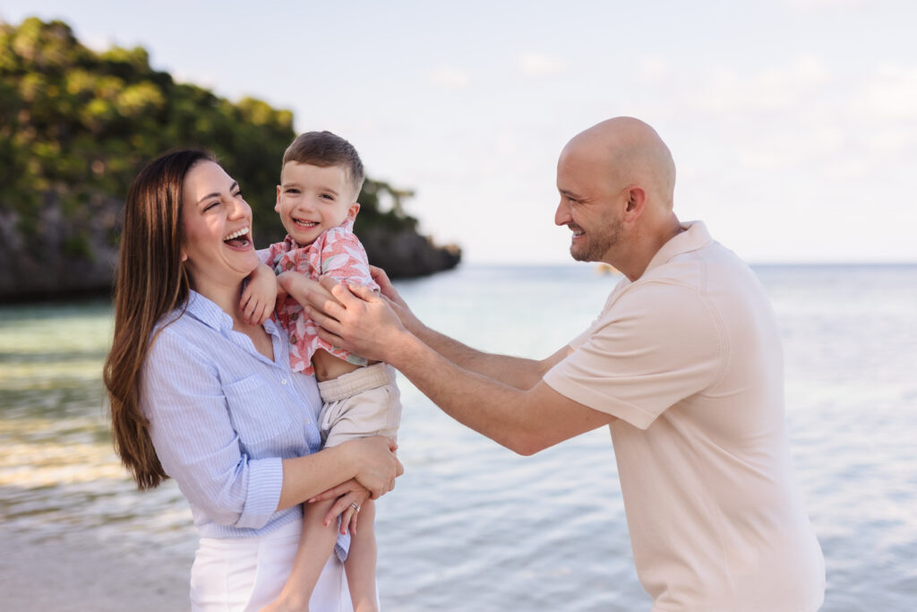 A couple with their young son laughing on the beach