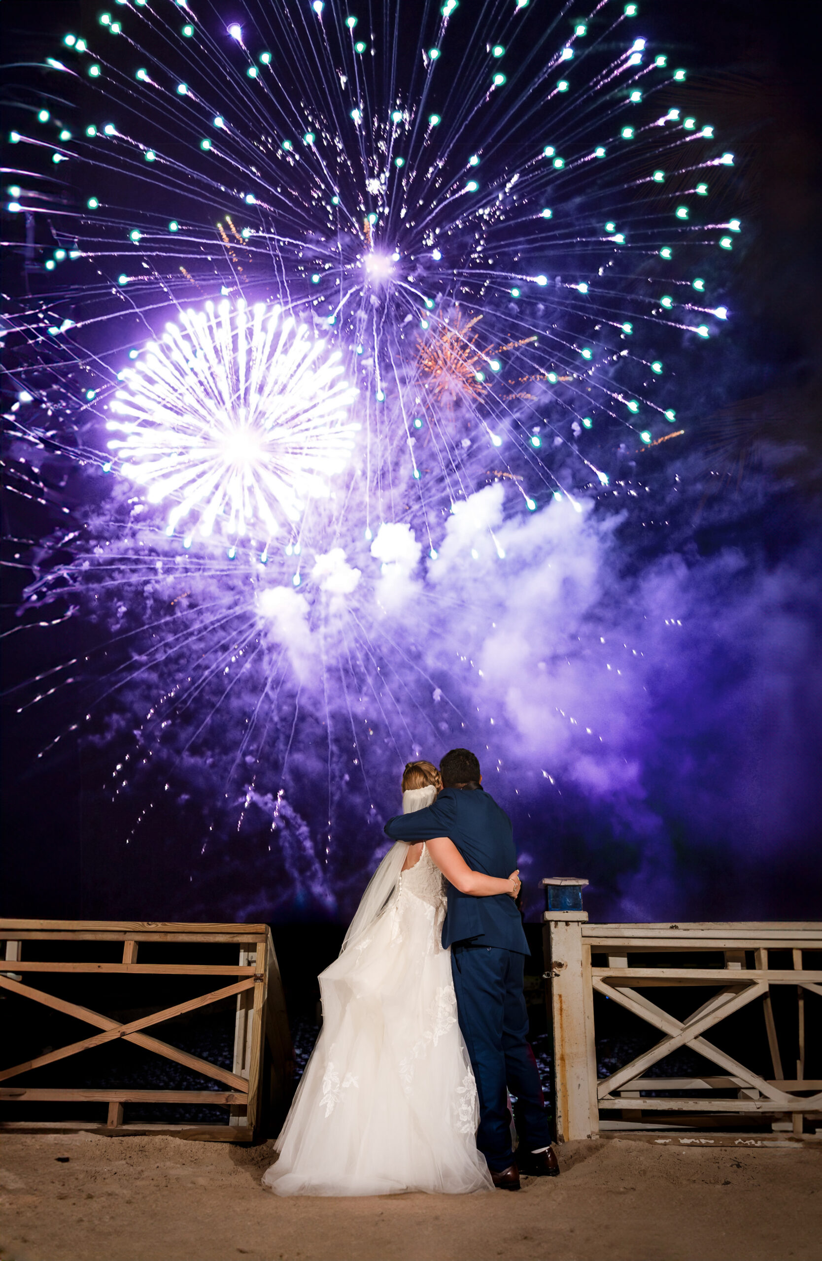 A couple embrace while watching fireworks.