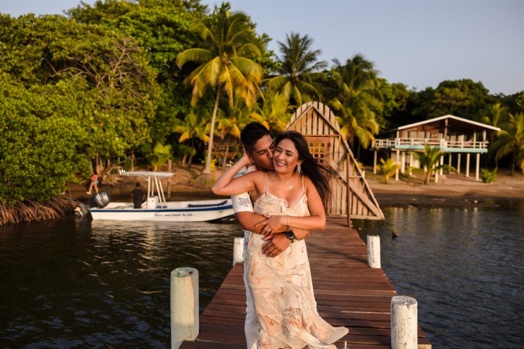 A couple embrace on a dock in Roatan after their Roatan proposal.