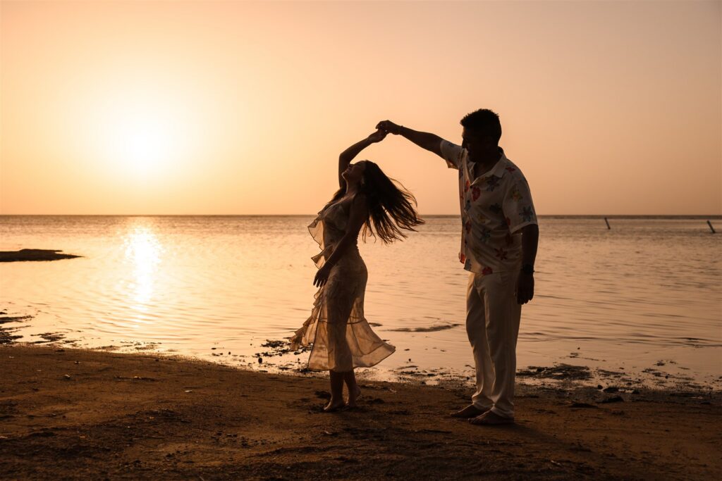 A man and woman dance in on the beach silhouetted against a Roatan sunset after their Roatan proposal.