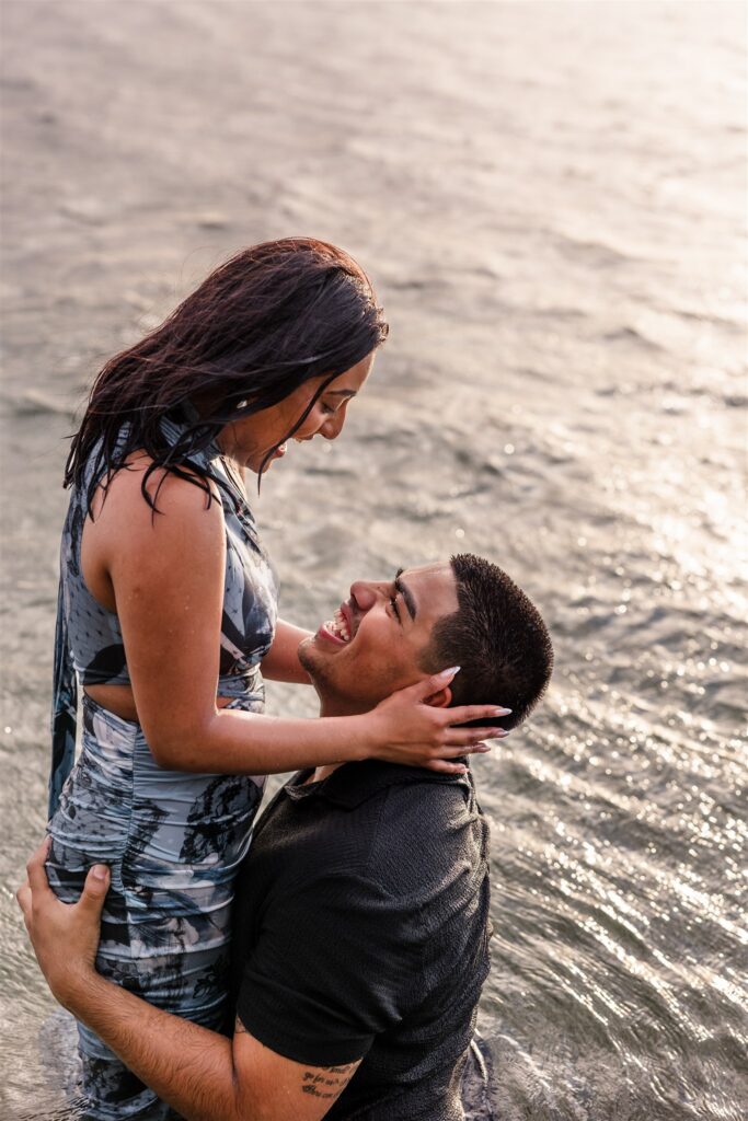 A couple plays and laughs in the water in Roatan after their Roatan proposal.