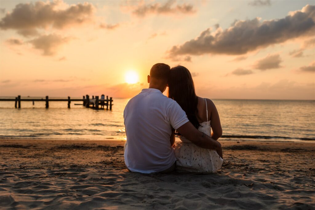 A recently engaged couple sit and watch the sunset in Roatan after their Roatan proposal.