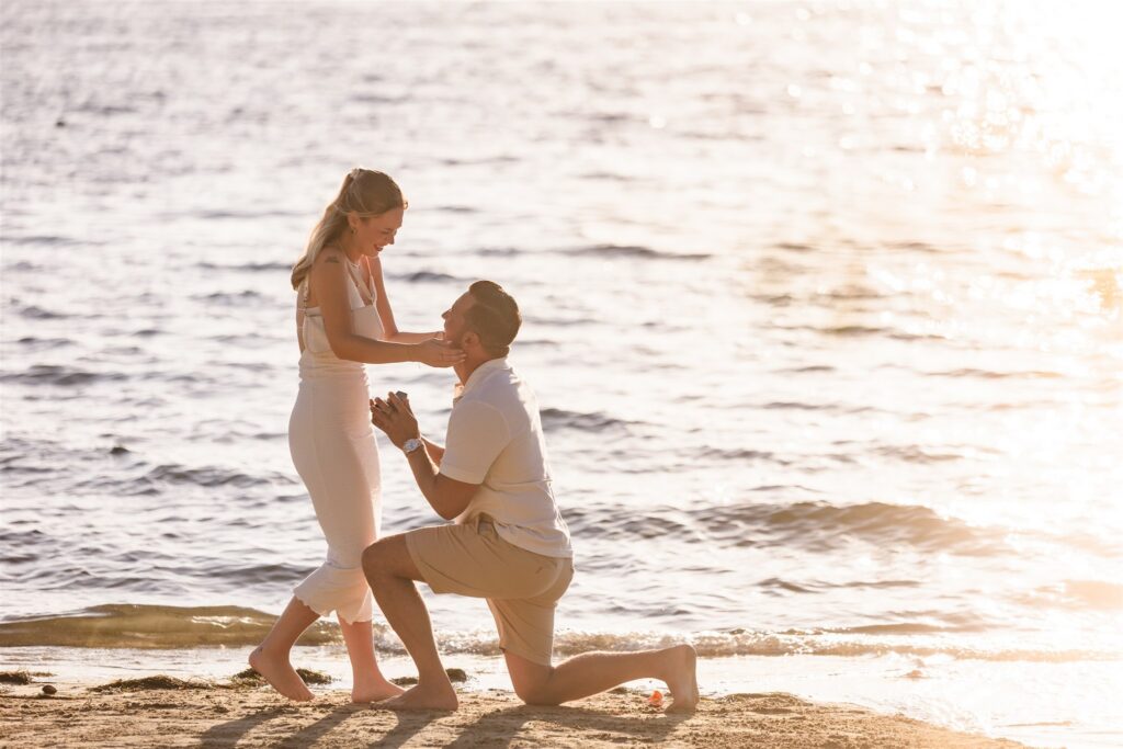 A woman embraces her fiance while he proposes to her on the beach in Roatan.