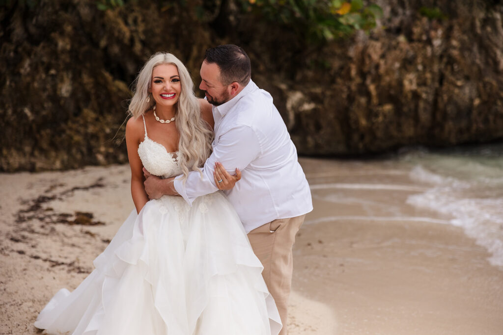 A couple plays on West Bay Beach during their Roatan trash the dress photo session.  