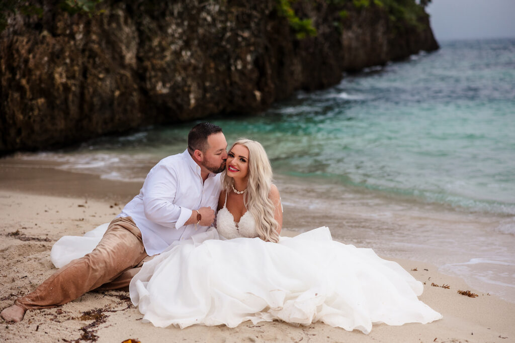 A couple sits in the sand on West Bay Beach during their Roatan trash the dress photo session.  