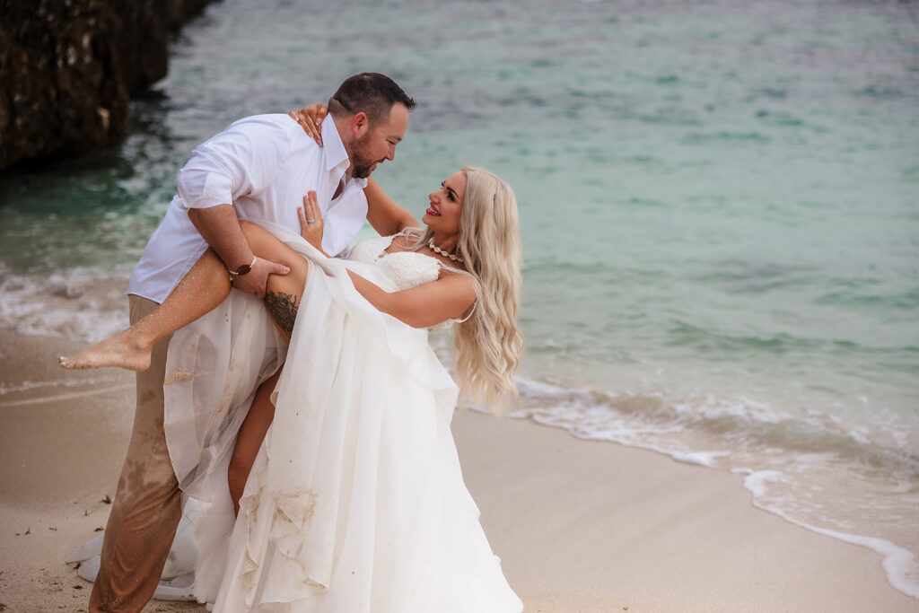 A groom dips his bride on West Bay Beach during their Roatan trash the dress photo session.  
