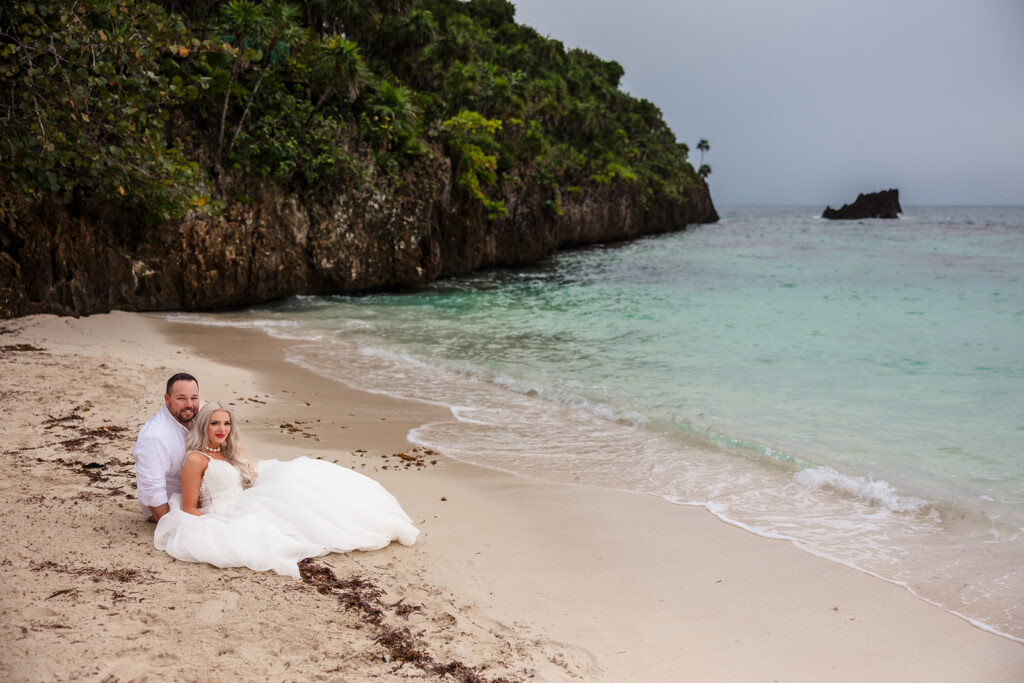A couple sits in the sand at West Bay Beach during their Roatan trash the dress photo session.  
