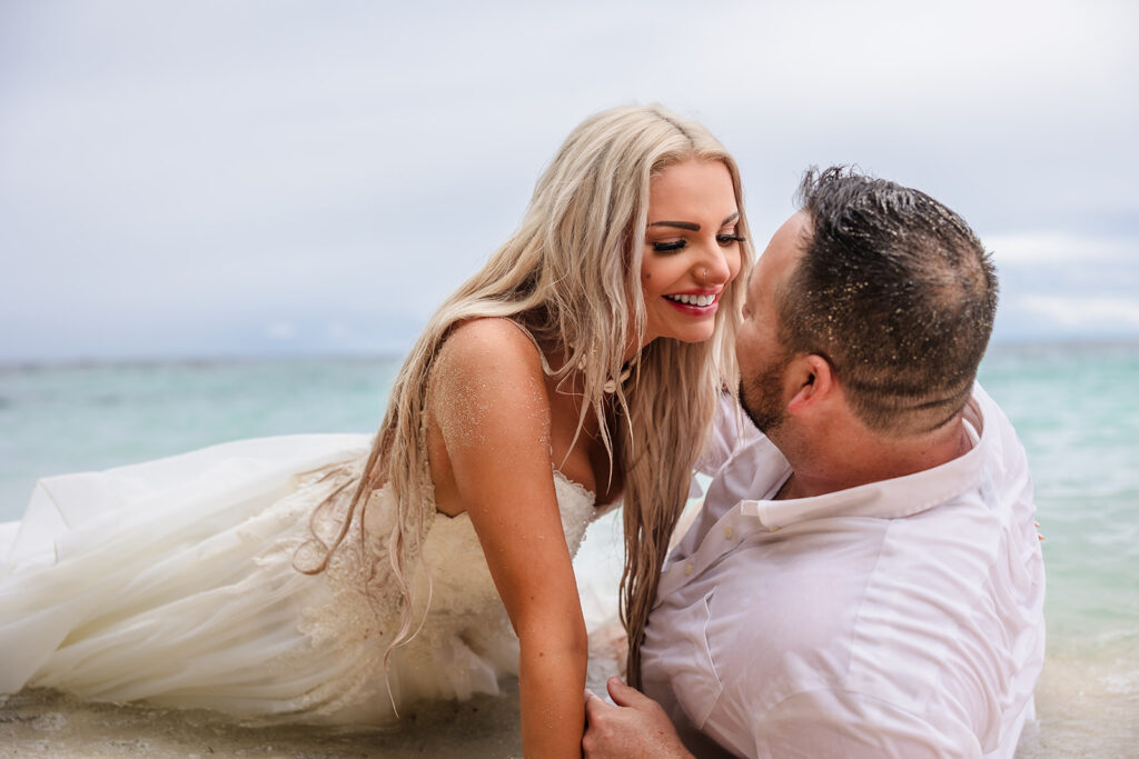 A couple lies on the beach at West Bay Beach during their Roatan trash the dress photo session.  
