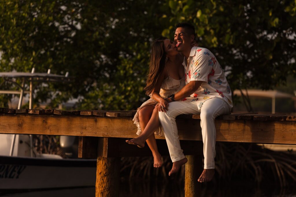 A couple sits on a dock and snuggles in Roatan after their Roatan proposal.